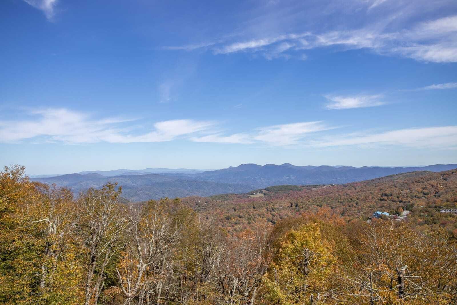 A mountainous landscape with autumn foliage and distant mountains under a clear sky.