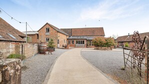 Un bâtiment situé en zone rurale, avec une allée de gravier menant à une porte en bois.