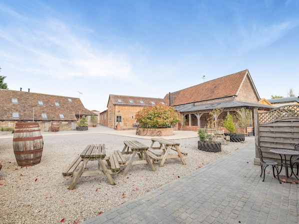 A courtyard with rustic buildings, wooden benches, and a gravel ground.