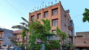 A hotel with a brick facade, a sign for 'Arham Inn', and a car parked in front. - Pioneer Plaza Jodhpur (Jodhpur)