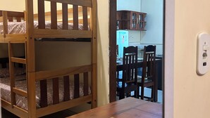Una cama litera con estructura de madera y un control remoto sobre una mesa de madera.