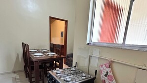 Una cocina con estufa a gas, una mesa de comedor con sillas y una ventana con persianas.