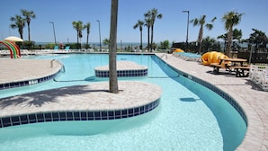 A clear swimming pool with tiled edges, palm trees, and a picnic table. - Beauty on The Beach! (Myrtle Beach)