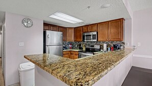 A kitchen with granite countertops, stainless steel appliances, wooden cabinets, and a built-in microwave. - Beauty on The Beach! (Myrtle Beach)