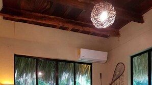Een slaapkamer met een bed, een lamp, een wandairconditioner en een decoratieve wandversiering.