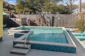 Ein rechteckiger Pool mit einer gefliesten Kante, einer kleinen Stufe zum Einsteigen und einer Metallleiter.