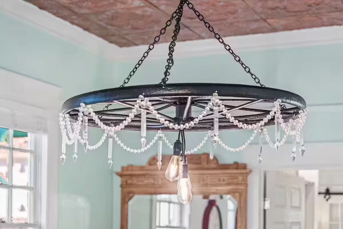 Een kroonluchter met een zwarte voet en heldere glazen lampen, hangend aan een ketting aan het plafond.