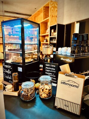 Mostrador de café con una exhibición de pasteles, una máquina de café y un tablero de menú.