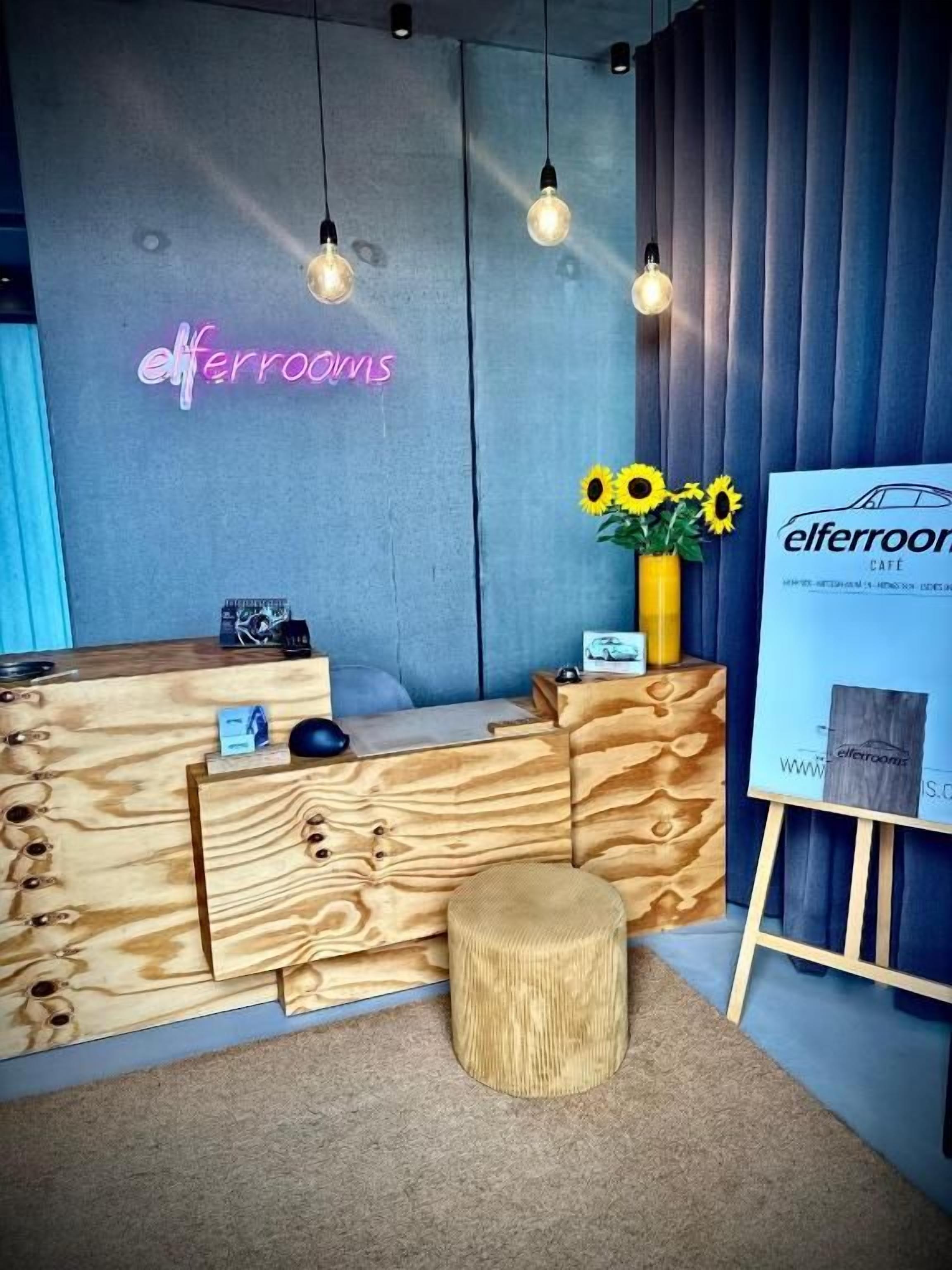 Un comptoir d’accueil au design en bois, un panneau lumineux néon et une affiche.