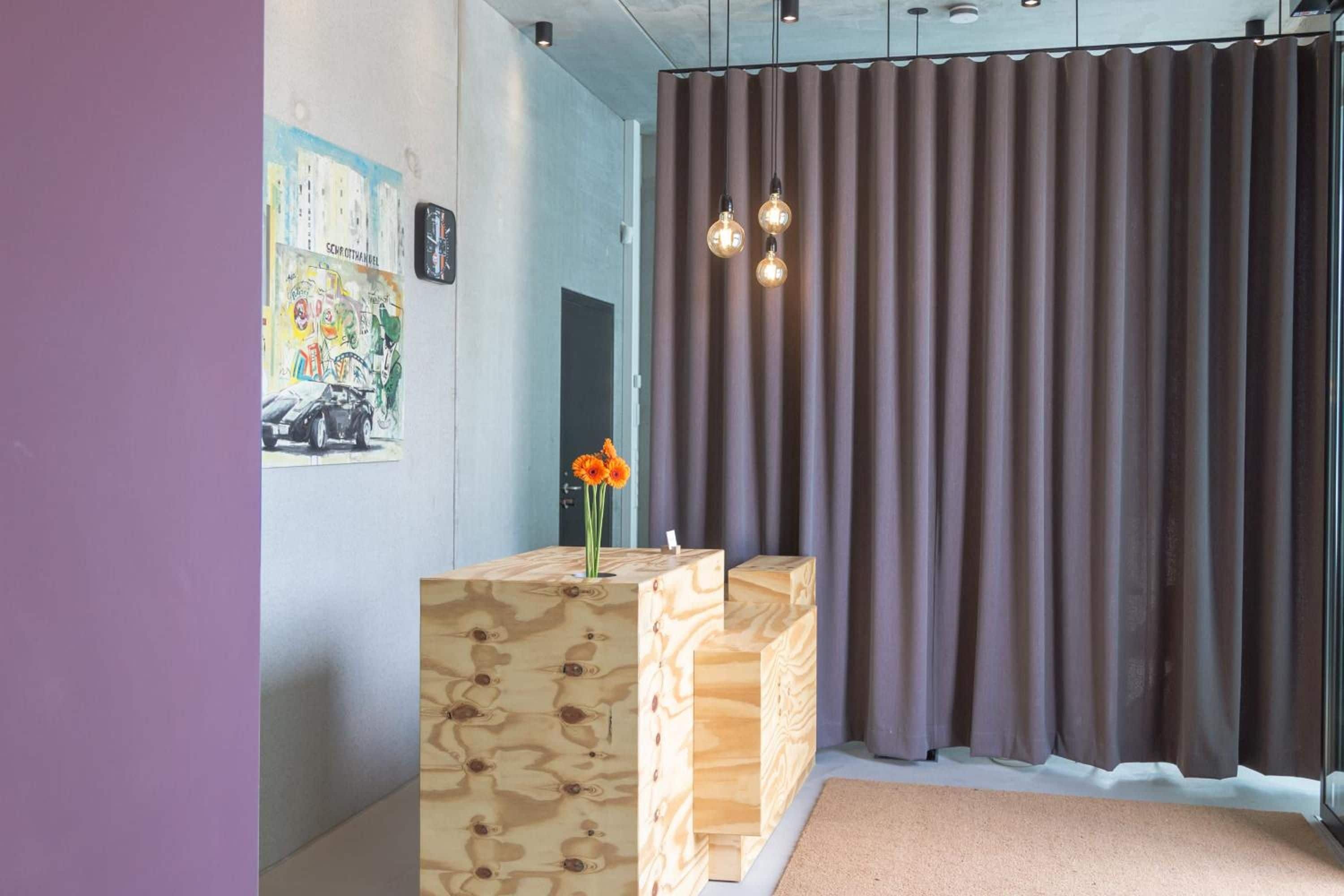 Un espace d’accueil avec un comptoir en bois, un tableau accroché au mur et un rideau.
