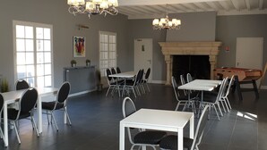 A dining area with multiple tables and chairs, a fireplace, and a foosball table.