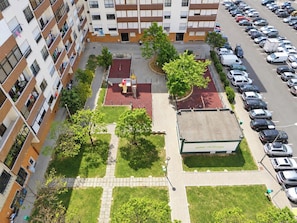 Ein mehrstöckiges Wohngebäude mit Parkplatz und einer kleinen Spielanlage.