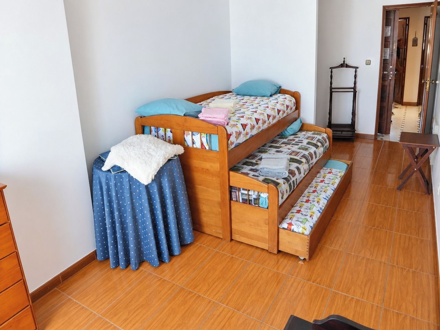 A room with a bunk bed, a small table, and a chair.