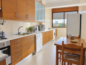 Une cuisine moderne avec des meubles en bois, un lave-vaisselle, un évier et un coin repas comprenant une table et des chaises.