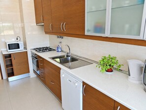 A modern kitchen with wooden cabinets, a stainless steel sink, a microwave, a gas stove, and a dishwasher.