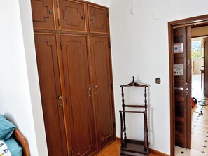 Une pièce avec une grande armoire en bois, une petite chaise en bois et un sol carrelé.