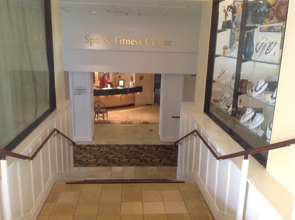A staircase leading to a spa and fitness center with a reception desk and jewelry display.