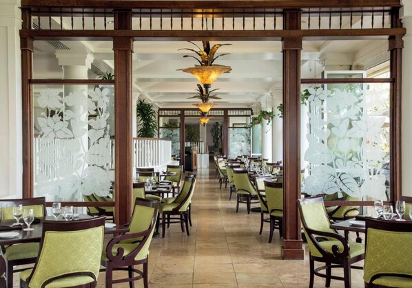 Un restaurant avec une grande table centrale, des piliers en bois et des panneaux de verre décoratifs.