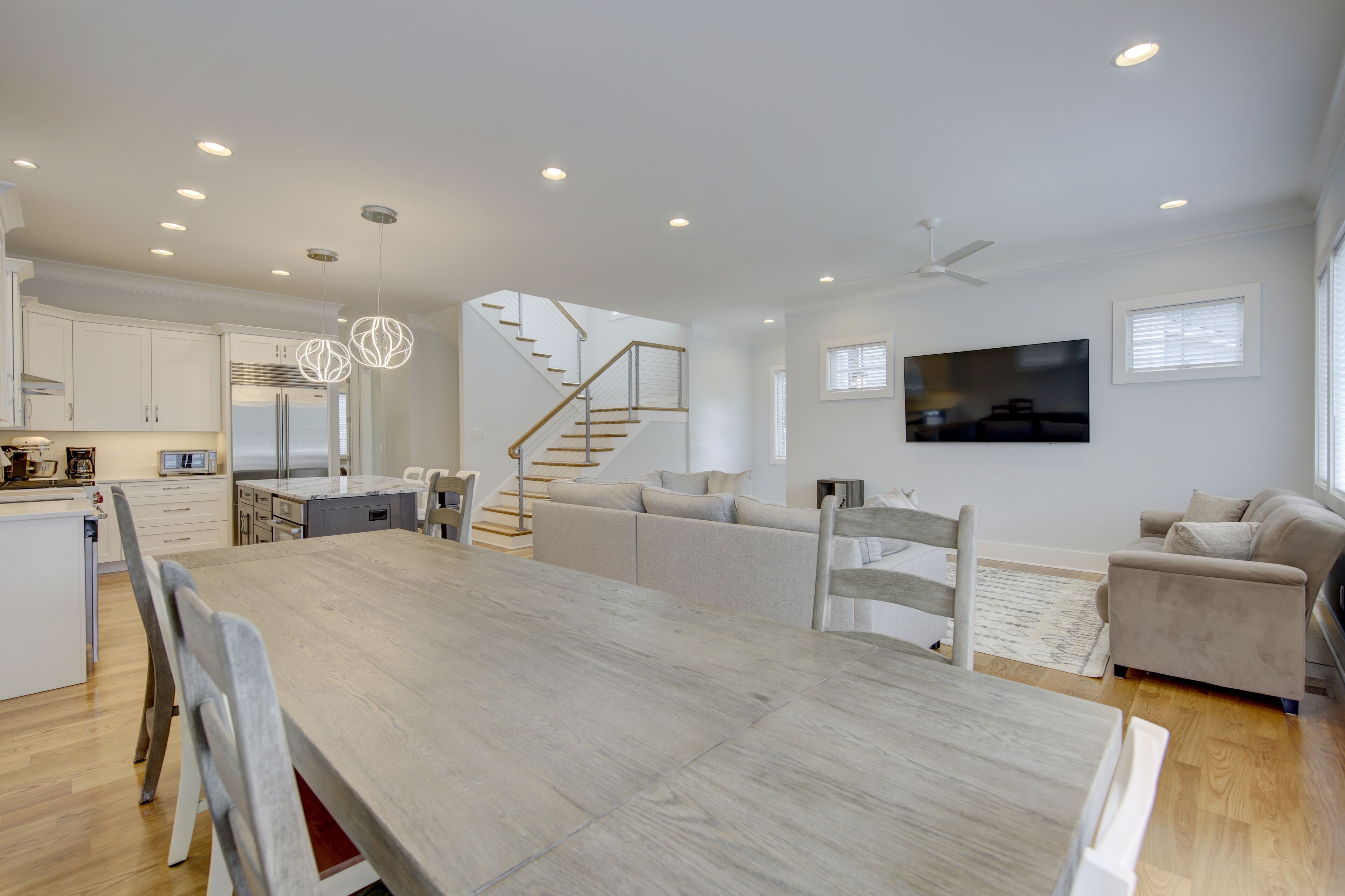 Una cocina moderna con armarios blancos, una mesa de comedor de madera y una escalera que lleva a una zona de altillo.