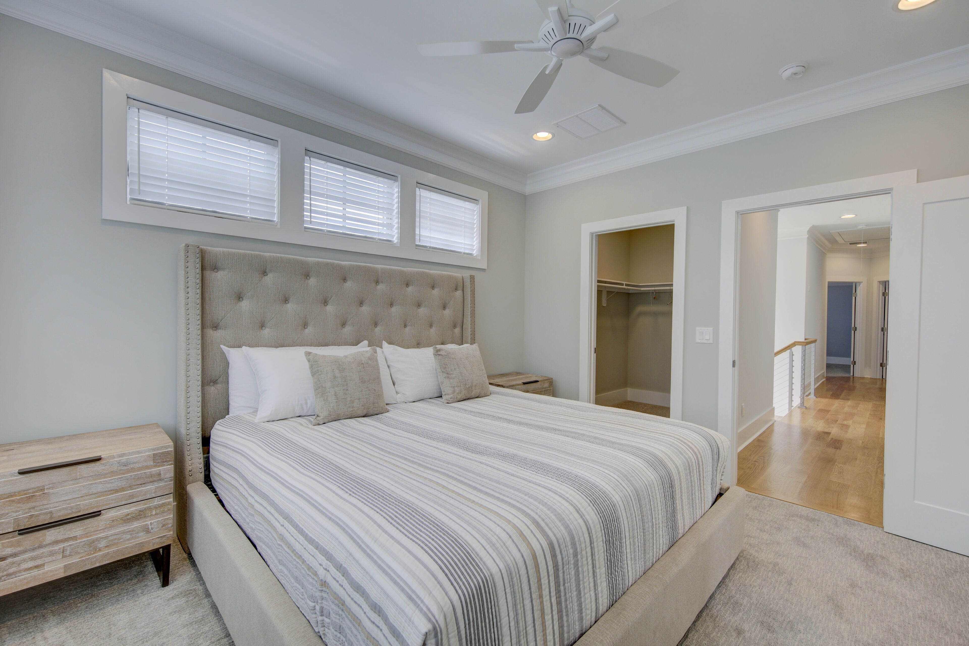 A bedroom with a large bed, a nightstand, a ceiling fan, and a walk-in closet.