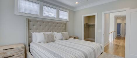 A bedroom with a large bed, a nightstand, a ceiling fan, and a walk-in closet.