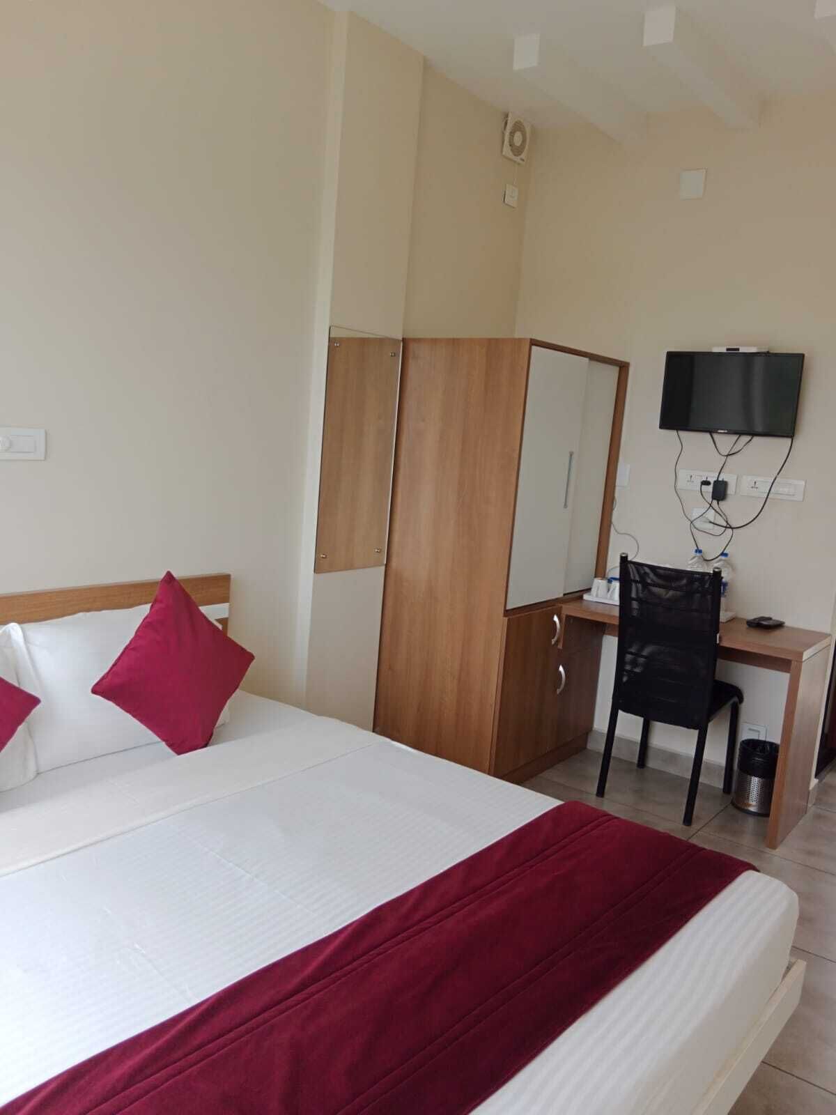 Una habitación de hotel con cama, escritorio, silla, televisor y armario.