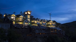 A multi-story house with a prominent tower and wind turbine on a hillside. - Foggy Knolls Resort (Meenachil)