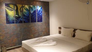 A hotel room with a large abstract painting on the wall, a neatly made bed with white linens, and a textured wall.