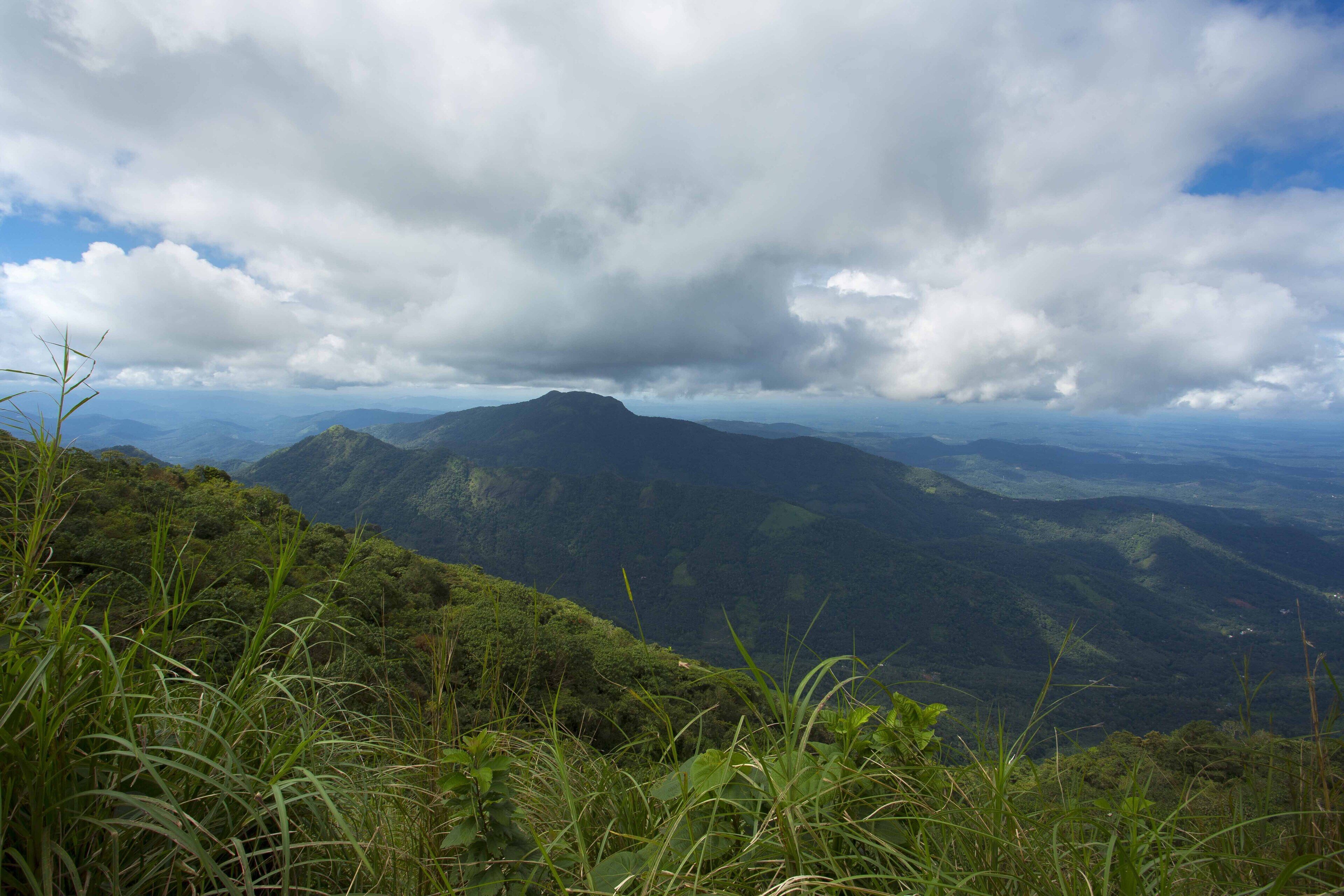 A mountainous landscape with lush greenery and a cloudy sky.