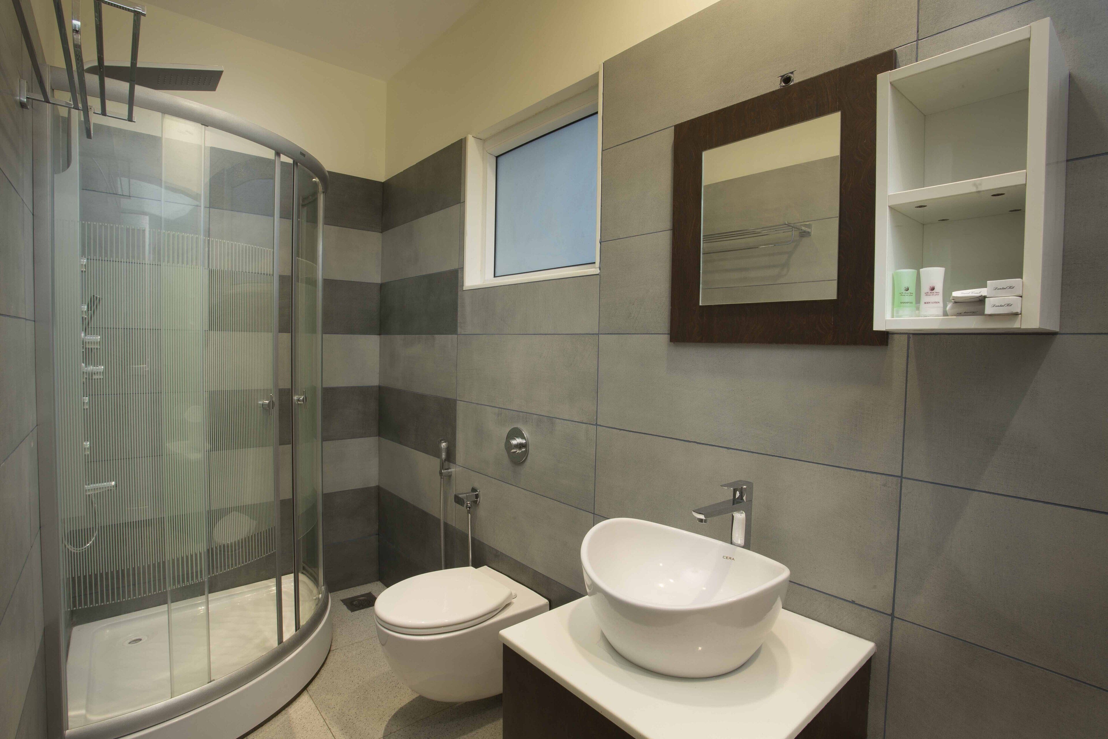 A modern bathroom with a glass-enclosed shower, a white sink, and a small window.