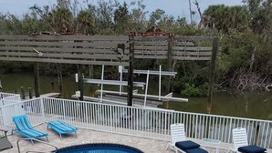 A swimming pool with lounge chairs and a wooden deck. - Water Views, Pool, Private boat dock, Walking distance to Times Square (Fort Myers Beach)