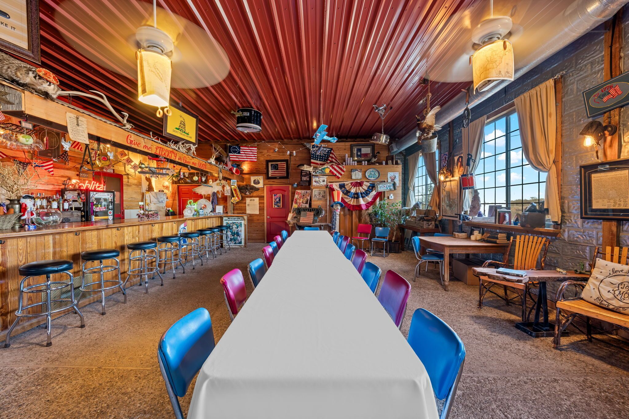A bar with a long counter, stools, and a large table with chairs.