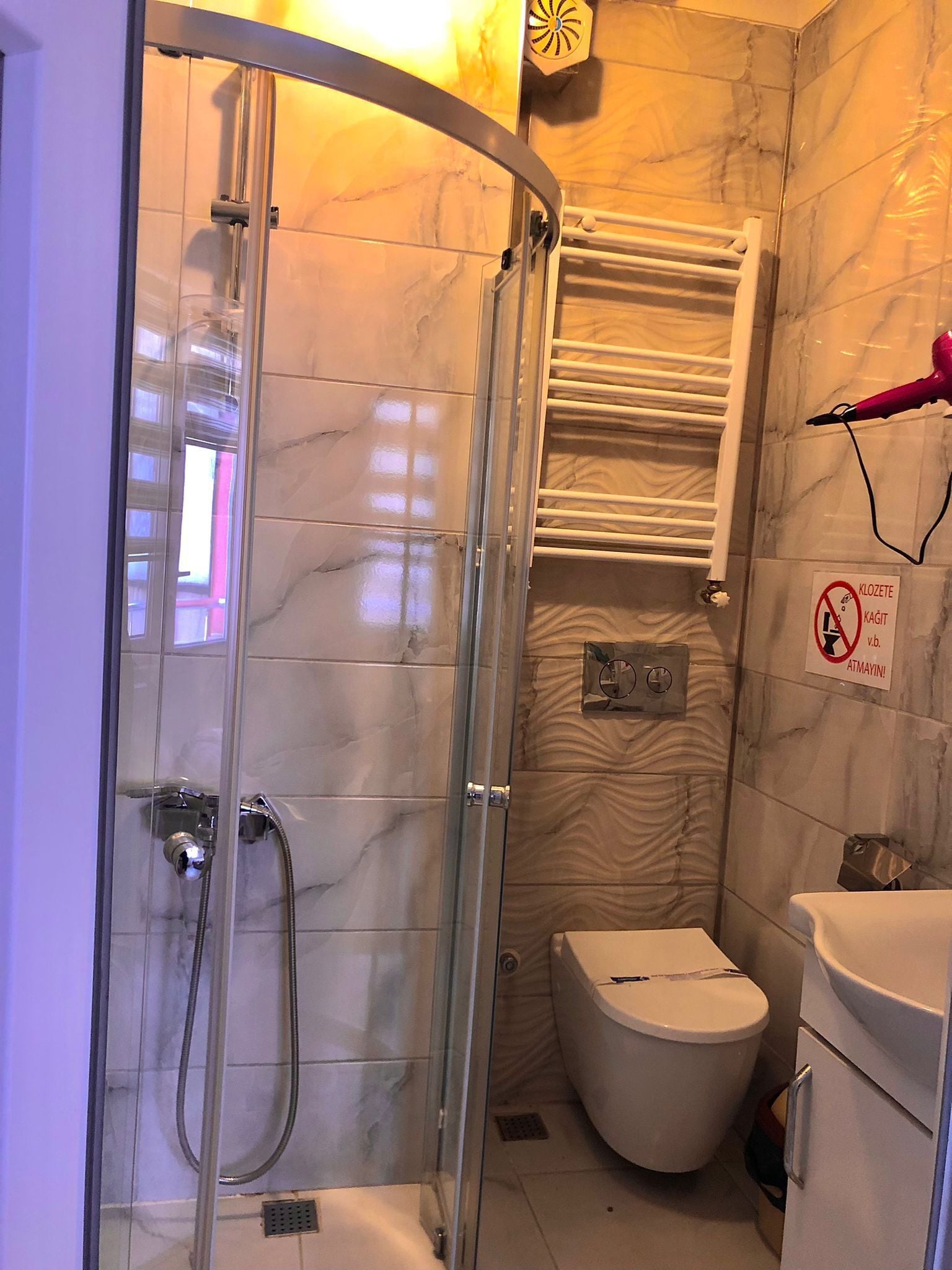 Un baño con ducha envuelta en vidrio, inodoro y lavamanos.