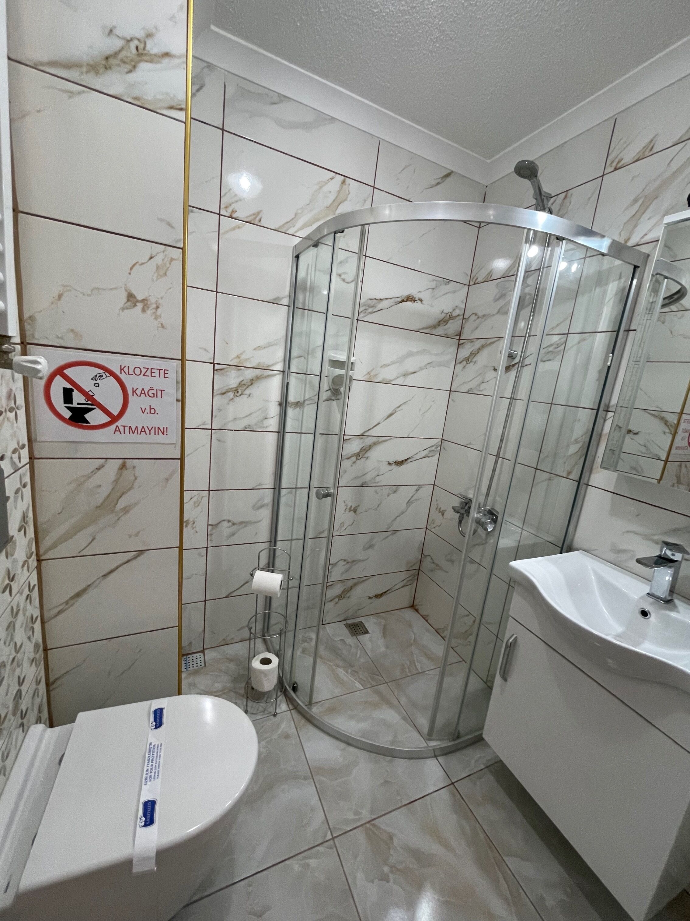 A bathroom with a glass shower enclosure, a toilet, and a sink.