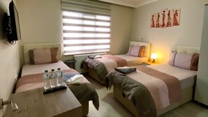 A hotel room with two single beds, a wooden desk, a TV, and a window with blinds. - Tekinler Otel (Balikesir)