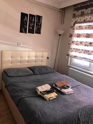 A bedroom with a bed, pillows, a bedside lamp, and artwork on the wall.