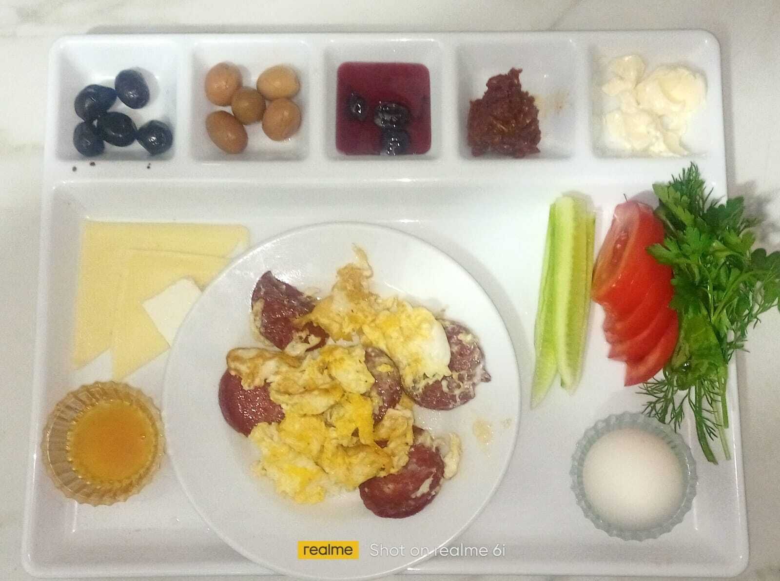 Una bandeja de desayuno con huevos revueltos, salchichas y diferentes acompañamientos.