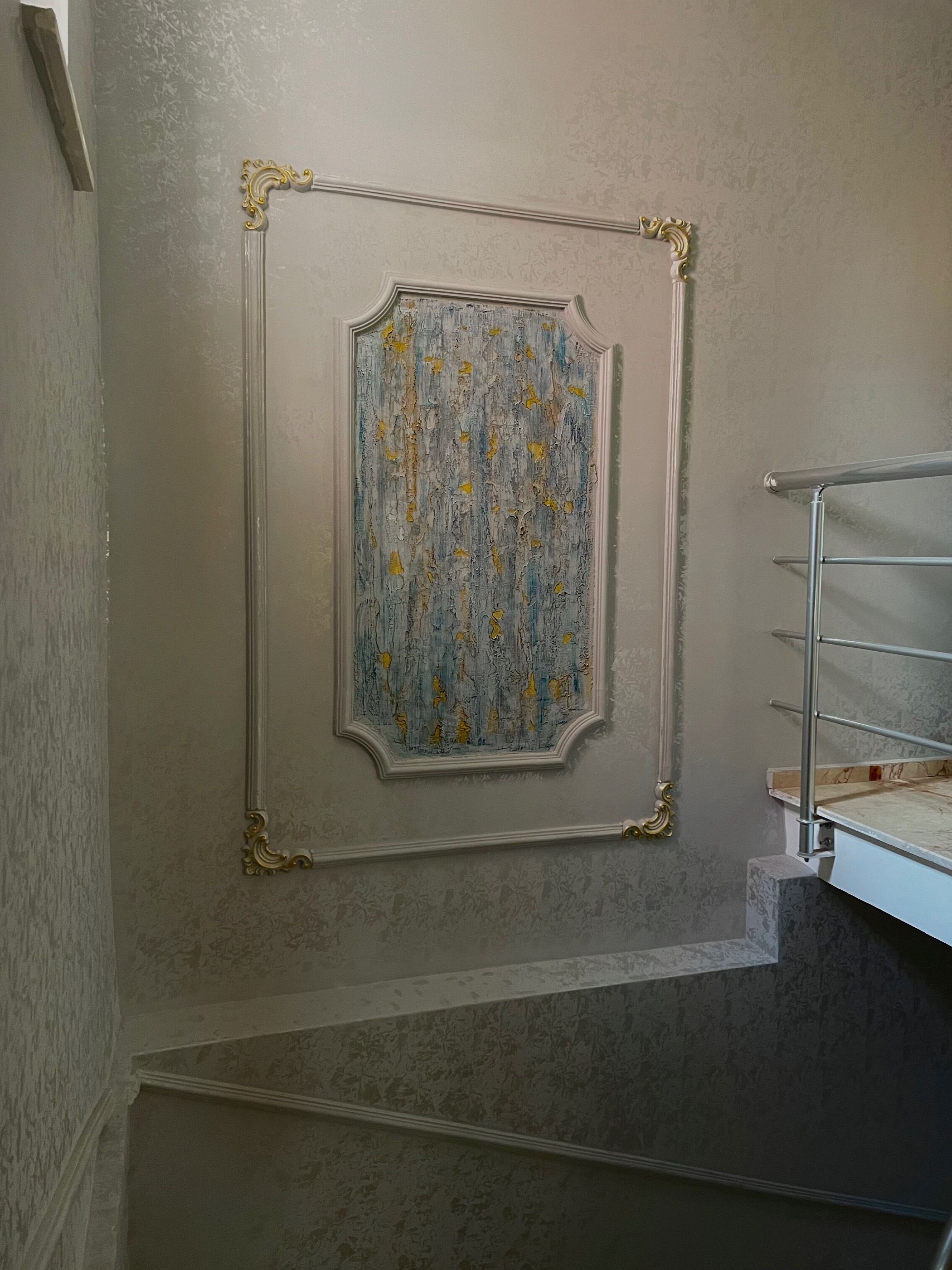 Eine Treppe mit einer verzierten Wandverkleidung und einem Metallgeländer.