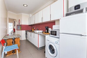 A compact kitchen with a washing machine, a microwave, and a coffee maker.