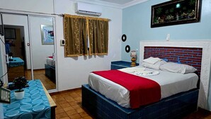 A bedroom with a bed, a dresser, a mirror, and a window with curtains. - Hotel Kevin (Puerto Plata)