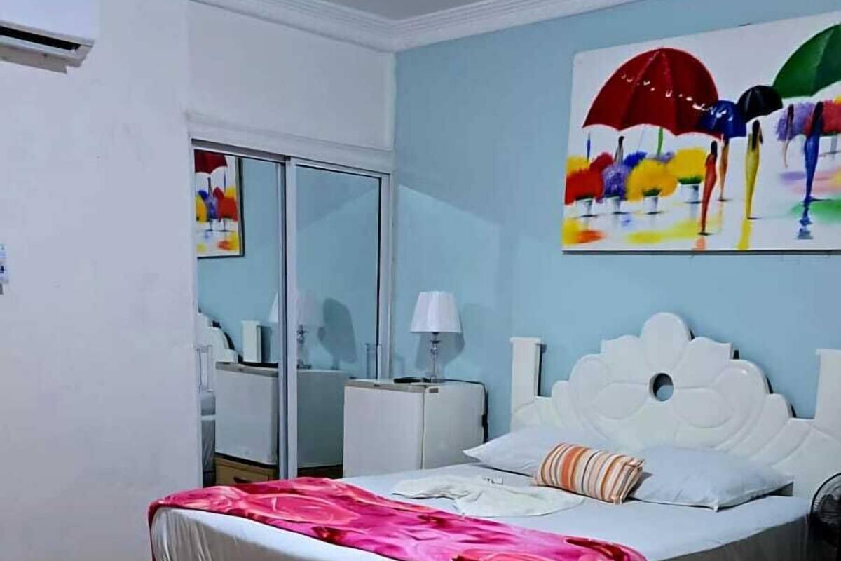A bedroom with a bed, a nightstand, a lamp, and a painting on the wall.