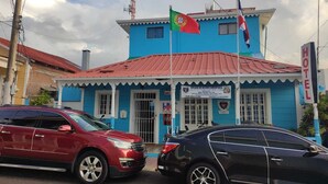 A blue building with a red roof, a flag, and a sign that reads "BRIGADA DE ACCION COHUNITARIA HOTEL KEY". - Hotel Kevin (Puerto Plata)