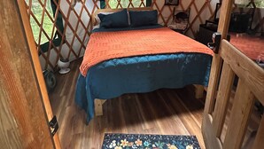Een slaapkamer in een joert met een bed, een raam en een houten vloer.