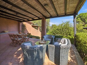 An outdoor patio with wicker furniture, a table, and a view of greenery. - Vacation home Dalila by Interhome (Porto Istana)