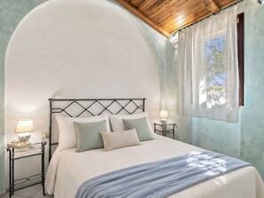Une chambre à coucher avec un lit, deux tables de chevet et une fenêtre avec des rideaux.