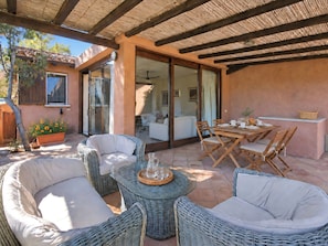 A covered outdoor seating area with wicker furniture, a glass table, and a dining table set for two. - Vacation home Dalila by Interhome (Porto Istana)