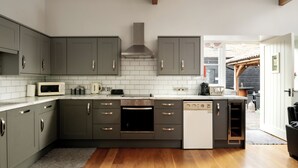 A modern kitchen with grey cabinets, a built-in oven, microwave, and dishwasher. - Webbington Farm Holiday Cottages (Axbridge)