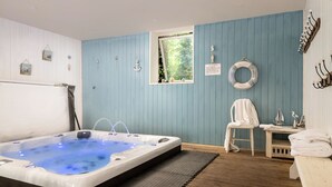 A room with a hot tub, a window, a chair, and a bench. - Webbington Farm Holiday Cottages (Axbridge)
