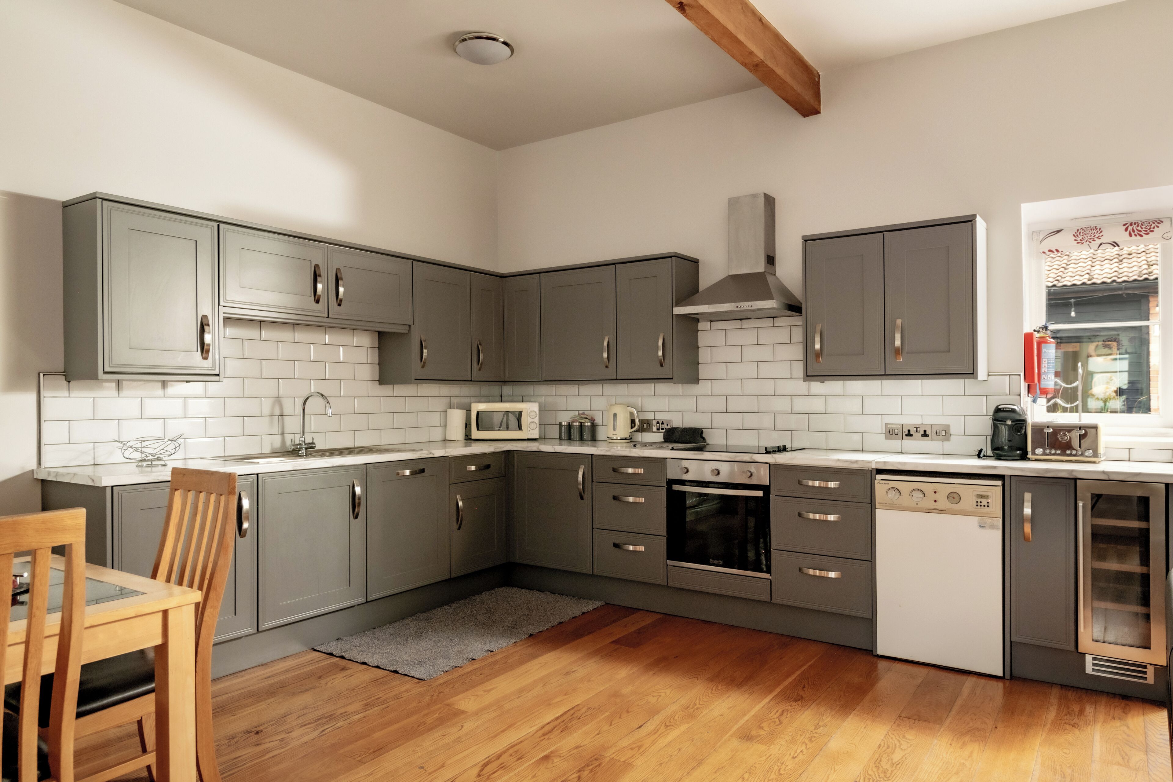 Una cucina moderna con mobili grigi, forno integrato, lavastoviglie e microonde.