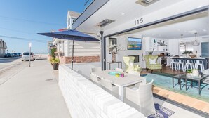 Una moderna camera d'hotel con un balcone, una zona pranzo e una cucina visibile attraverso le porte in vetro.